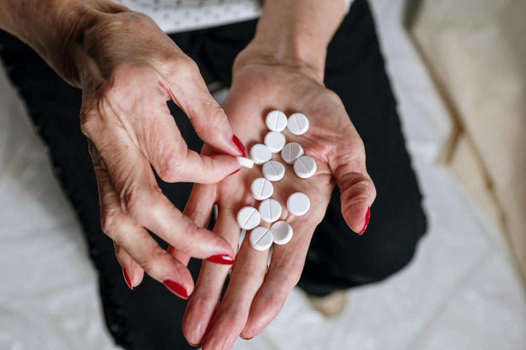person holding white round medication pill